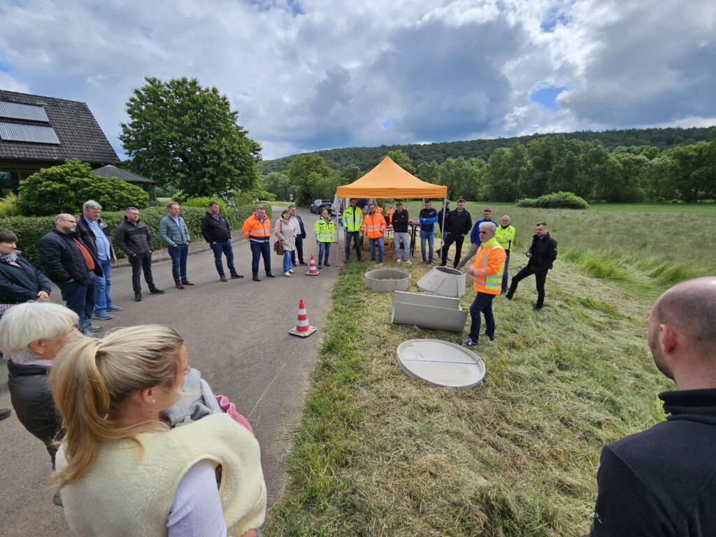 Baustellenvorführung einer Schacht-in-Schacht-Sanierung mit dem DURA.PORT-System in Twistetal-Berndorf. Vertreter von Kanalnetzbetreibern beobachten die Sanierung geschädigter Abwasserschächte durch Polymerbeton-Tübbinge.