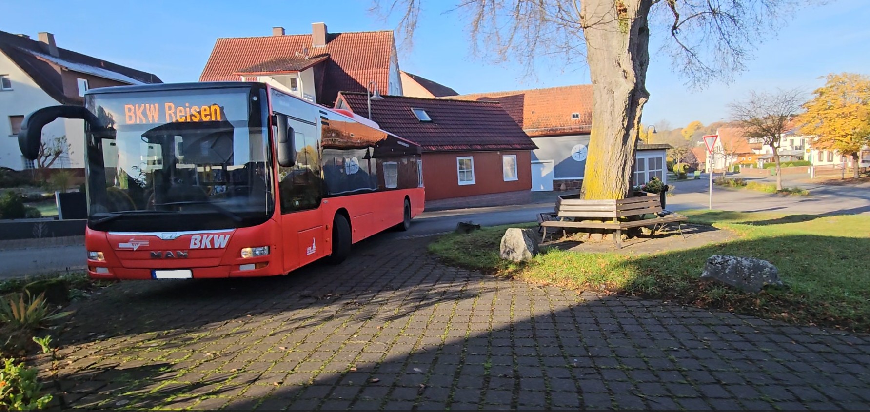 Ein roter Linienbus der BKW fährt im Rahmen eines Fahrversuchs durch den Bereich der geplanten Buswendeschleife in der Ortsdurchfahrt Willersdorf, um die zukünftige Verkehrsführung und die Nutzbarkeit der vorgesehenen Infrastruktur für den öffentlichen Personennahverkehr zu überprüfen.